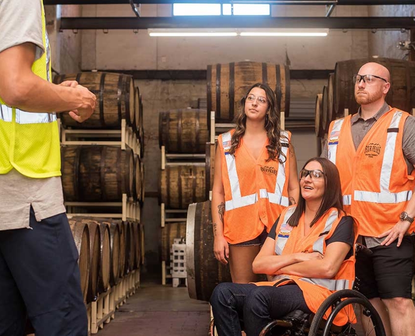 Three employees, on of whom is in a wheelchair are listening to their boss explain something.